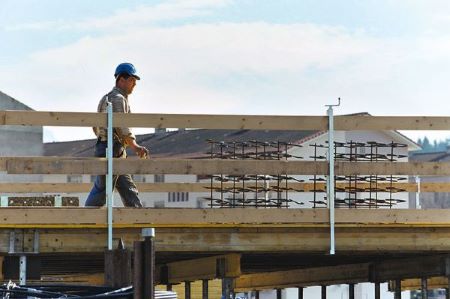 Male builder on a construction site walking on a temporary wooden bridge