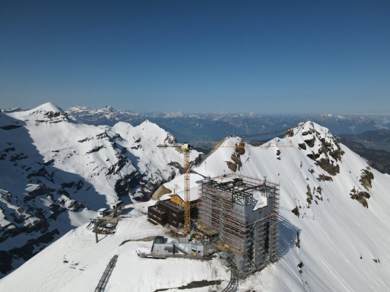 Aerial view on a high altitude resort with crane, including cable car terminal station, on a shiny weather day