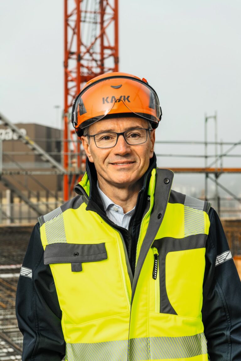 Gian-Luca Lardi, chairman of the SBV, in builder outfit on a construction site. Crane in the background.