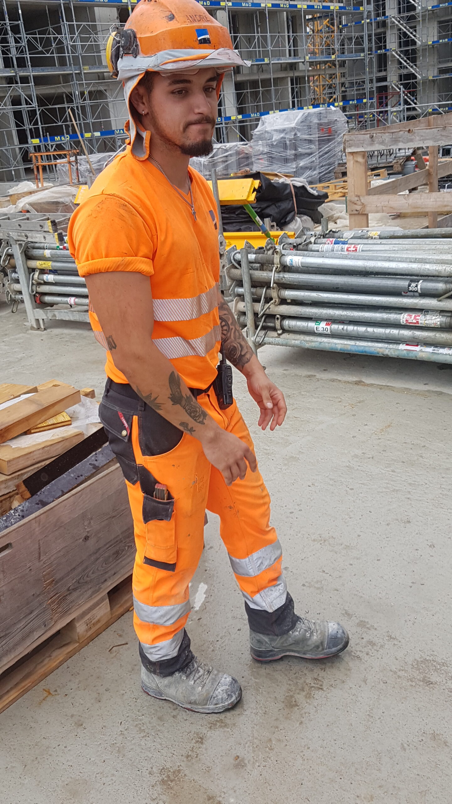 Young construction worker in orange with helmet completed with front visor and cloth neck protection