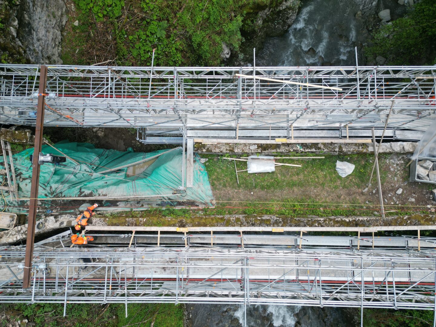 View from above of a bridge hugged by unleaning scaffoldings.